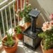 Kleiner Solarspringbrunnen auf Balkon mit Keramikschale und mediterranen Pflanzen